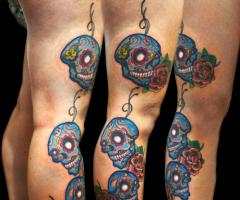 Tres calaveras mexicanas entre rosas