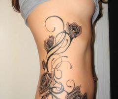 Tatuaje de rosas y lazos en cintura