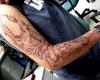 Tatuaje guitarra desgarrando la piel del brazo