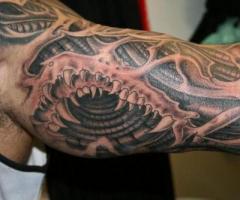 Biomechanical arm tattoo with shark teeth
