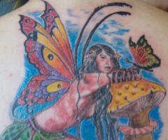 Hada arrodillada sobre hongo con mariposa