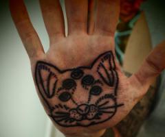 Tatuaje de lineas de rostro de gato en la palma de la mano