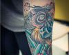 Forearm covered with blue waves, flowers and a black and golden koi fish