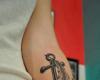 Ancla en sombras con una pluma en antebrazo
