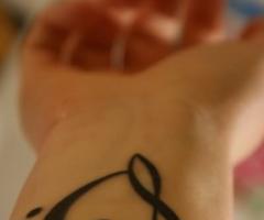 Tatouage sur le poignet de symboles musicaux formant un coeur