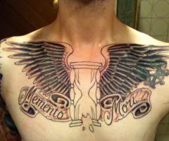 Schöne Tattoo auf seiner Brust aus zwei Flügeln mit einer Sanduhr