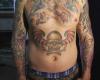 Bunte Tattoo auf dem Nabel eines Schädels mit zwei roten Flügeln