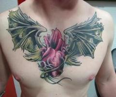 Tattoo auf der Brust ein Herz mit große grüne Flügel