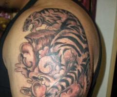 Große Tätowierung auf dem Arm eines Tigers, umgeben von Wolken des orientalischen Stil