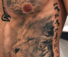 Tatuaje realista de León y letras chinas