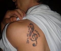 Tatuaje de clave de sol con frase