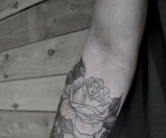 Gran tatuaje de rosa en el antebrazo de una mujer